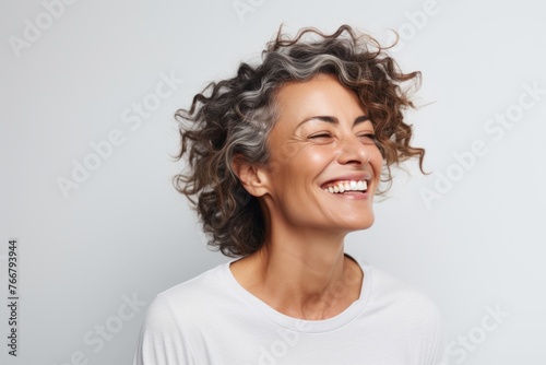 Close up portrait of a happy middle-aged woman laughing and looking up against grey background