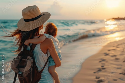 Rear view of woman holding baby on beach, summer travel, mother traveling with baby at seaside, mother looking at sea with baby