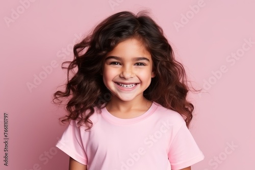 Portrait of a smiling little girl with curly hair over pink background