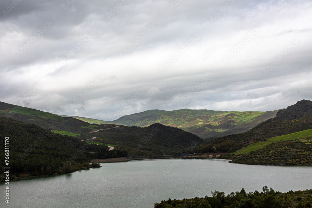Hills and forest on the lake with dramatic sky and clouds