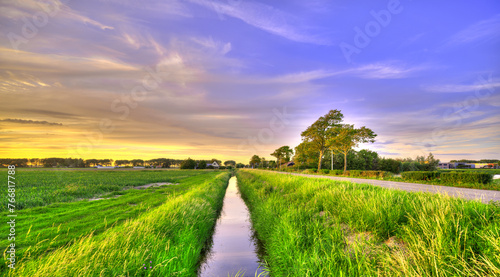 A small canal in a polder landscape in Holland at sunset.
