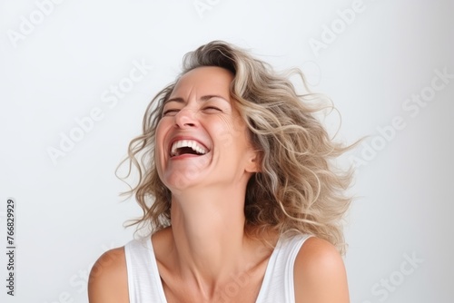 Portrait of a happy young woman laughing against a white background.