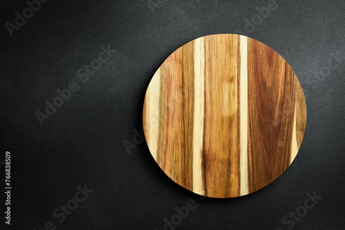 Kitchen wooden round board on a dark stone background. Top view. Free space for text.