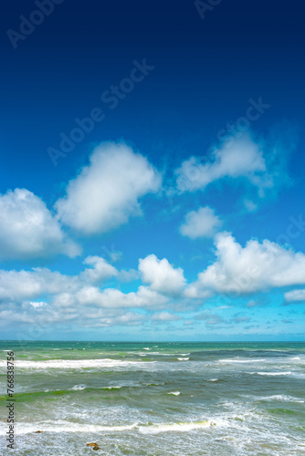 Cover page with oceanic seashore, at North Sea sandy beach, summer sunny day with big rolling waves, blue sky and copy space with gradient background