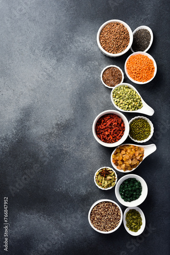 Banner with various superfoods in bowls on black stone background. Top view. Free space for text.