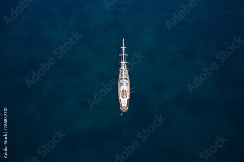 Expensive classic wooden sailing yacht on blue water top view. Large sailing yacht, top view. Anchorage sailing yacht on dark water top view.
