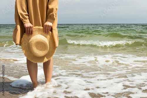 A girl in a dress walks on the beach in the summer.