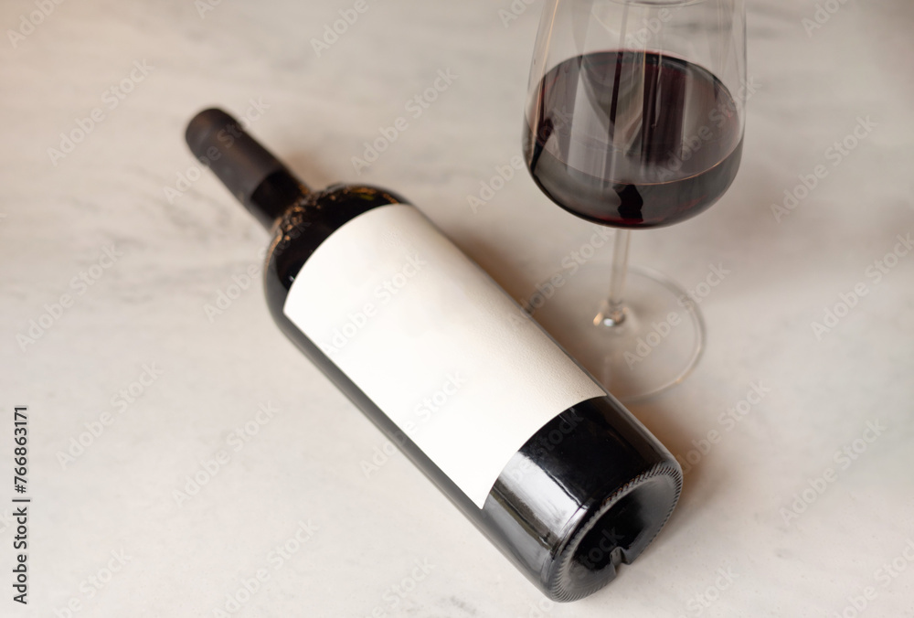 product photo of bottle with white label and glass with red white on hold in restaurant or in rack made from mirror. restaurant background, space for text, many bottles on shelf. product photo of bottle with white label and glass with red white on hold in restaurant or in rack made from mirror. restaurant background, space for text, many bottles on shelf.
