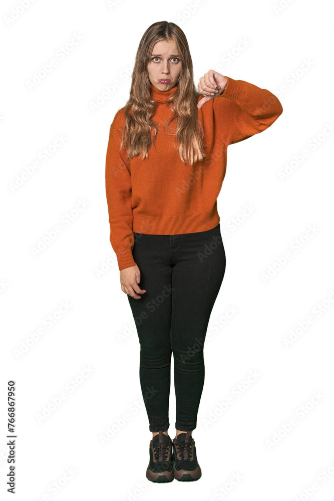 Studio portrait of a blonde Caucasian woman showing a dislike gesture, thumbs down. Disagreement concept. Studio portrait of a blonde Caucasian woman showing a dislike gesture, thumbs down. Disagreement concept.