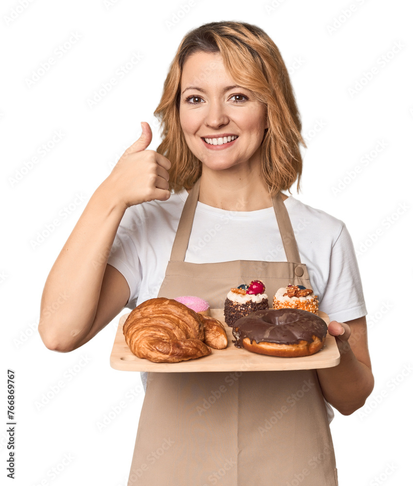 Middle-aged Caucasian woman baker with pastries smiling and raising thumb up Middle-aged Caucasian woman baker with pastries smiling and raising thumb up