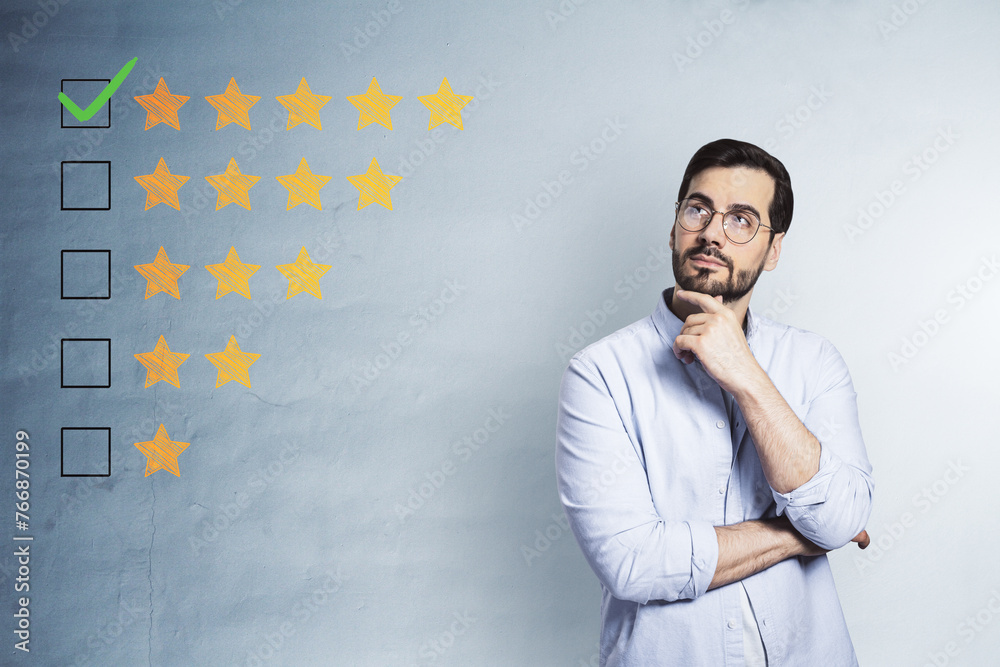Thoughtful young businessman with 5 star rating on concrete wall background. Customer service and excellent feedback. Thoughtful young businessman with 5 star rating on concrete wall background. Customer service and excellent feedback.