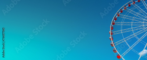 Panoramic banner with modern and big Ferris Wheel with red cars, at summer blue sky with turquoise, blue and green sunset colors with copy space