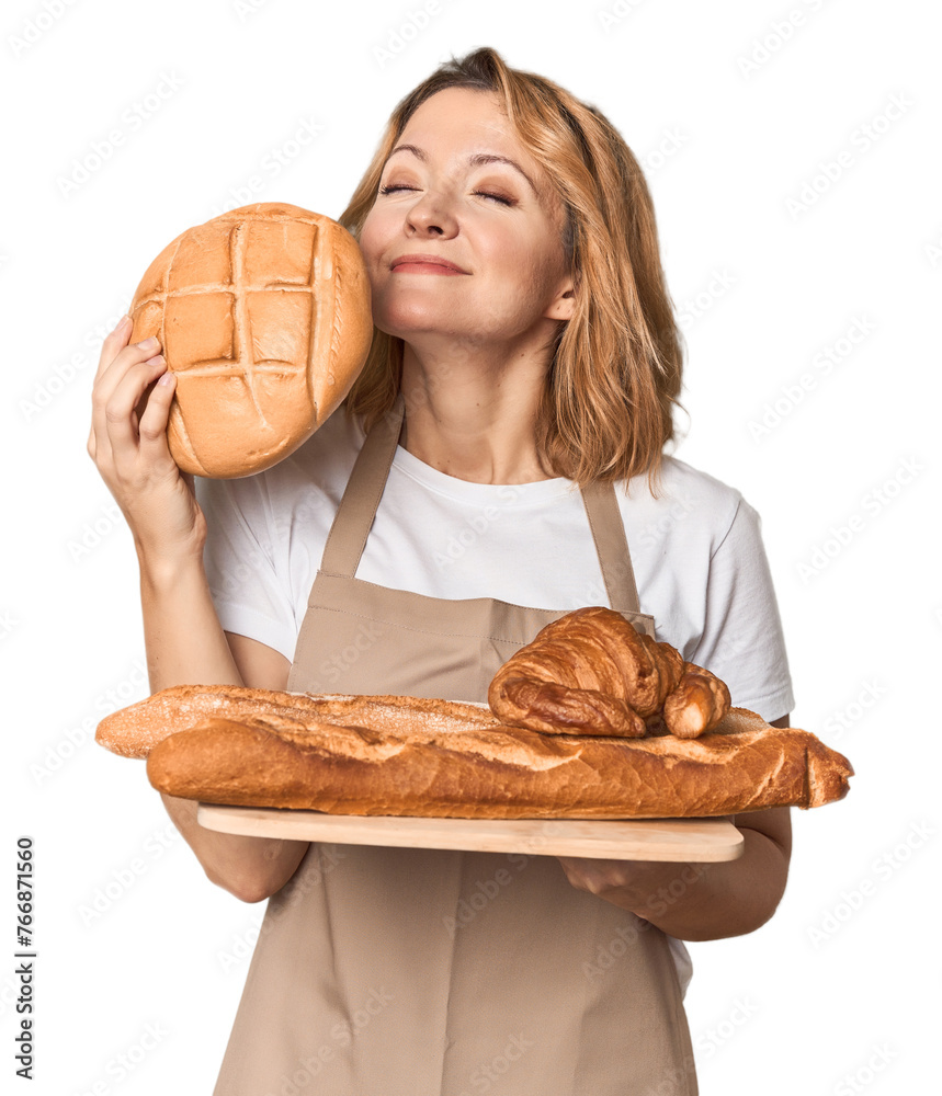Caucasian middle-aged female baker with bread tray in studio