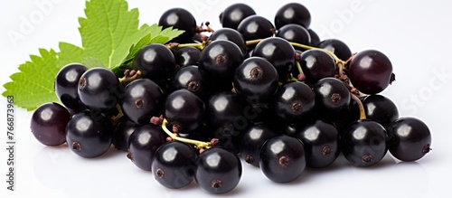 A bunch of black grapes, a seedless fruit, with a green leaf on a white background. This natural food is rich in antioxidants and perfect for snacking or adding to fruit salads