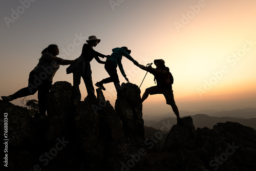 Silhouette of hikers climbing up on the mountain,team work and helping concept. Climber success.