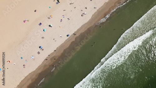 sandy beach on the coast of the atlantic with many people relaxing, waves crashing against the beach, porto, portigal, drone photo