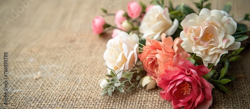 Artificial flowers arranged on a burlap background, close-up, can serve as a backdrop and greeting card.