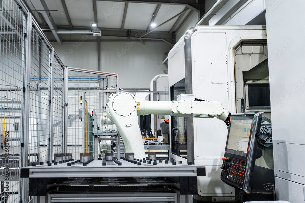 White robotic arm by CNC machinery in modern factory building White robotic arm by CNC machinery in modern factory building