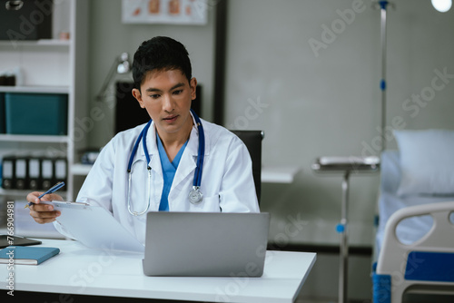Doctor working on laptop computer and tablet and medical stethoscope on clipboard on desk, electronics medical record system EMRs concept.