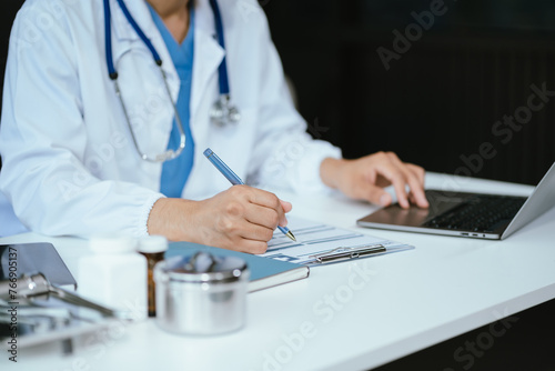 Doctor working on laptop computer and tablet and medical stethoscope on clipboard on desk  electronics medical record system EMRs concept.