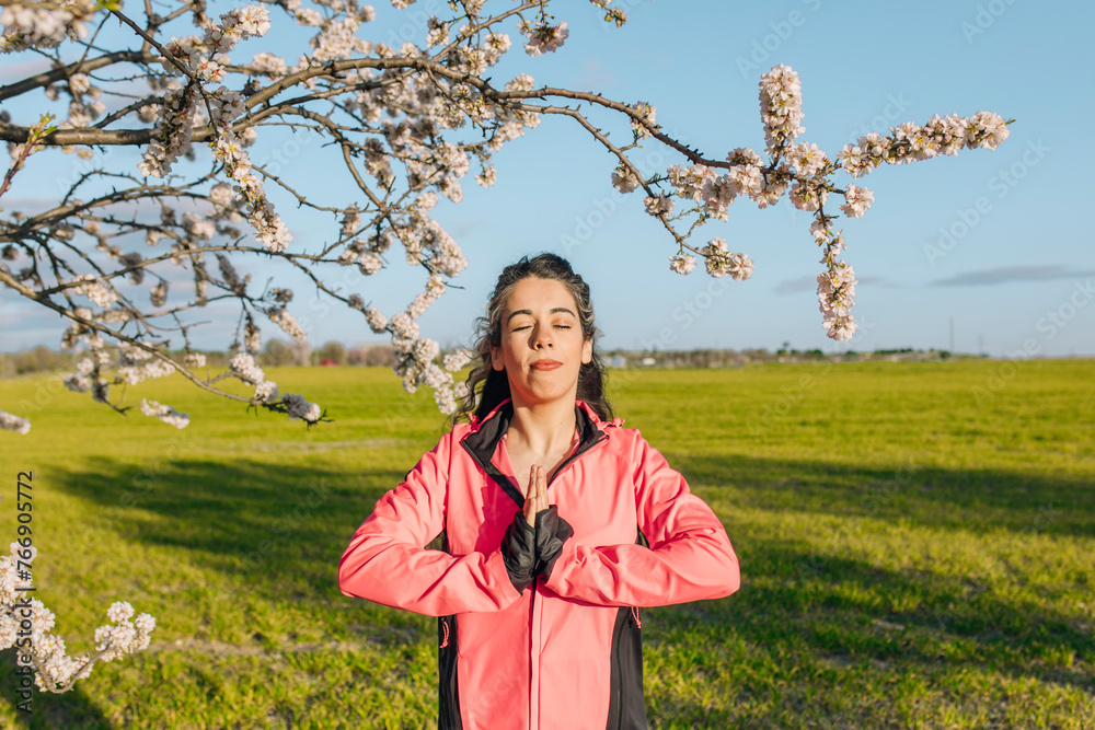 Woman meditating with eyes closed near almond blossom tree