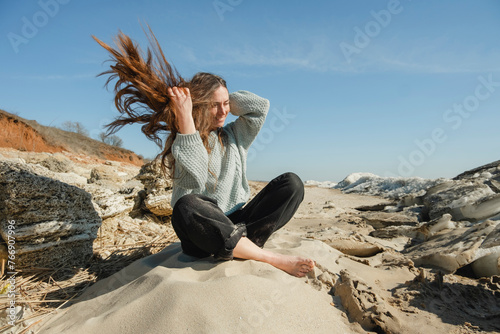 Woman sitting cross-legged on hill at windy sunny day photo