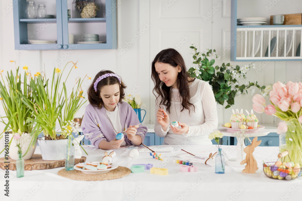 Woman looking at daughter decorating Easter eggs at home Woman looking at daughter decorating Easter eggs at home
