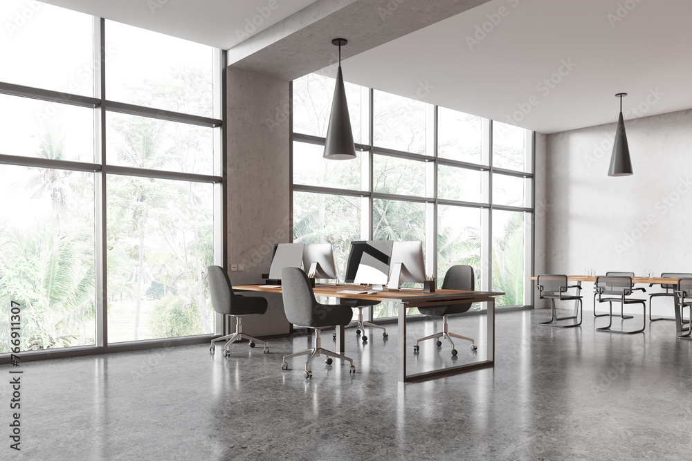 Modern office workspace interior with pc computers on desk with meeting table Modern office workspace interior with pc computers on desk with meeting table