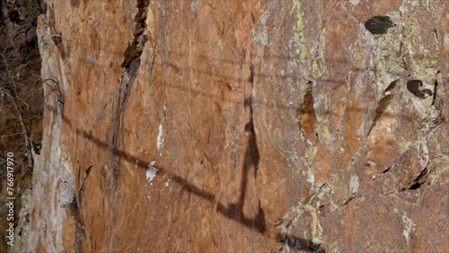 Man in body harnesses feature life-safety, attaches hooks to iron brackets, climbs rock, active lifestyle of people, mountaineering, viaferrata in mountains of pyrenees, High quality 4k footage photo