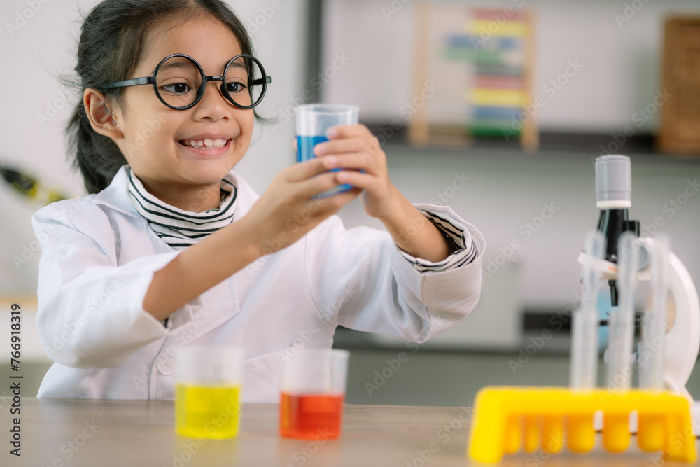 Little cute girl with a microscope holding a laboratory bottle with water experiment study scientists at school. Education science concept. Little cute girl with a microscope holding a laboratory bottle with water experiment study scientists at school. Education science concept.