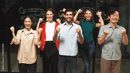 Group of businesspeople applause to celebrate successful project while looking at camera. Professional diverse business team standing at glass wall with marketing strategy, idea,plan. Tracery