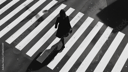 a woman on foot to work while crossing a zebra crossing in high angle, elegant fashion details