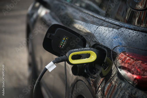 Closeup of black electric car charging at the station in the street © pixarno