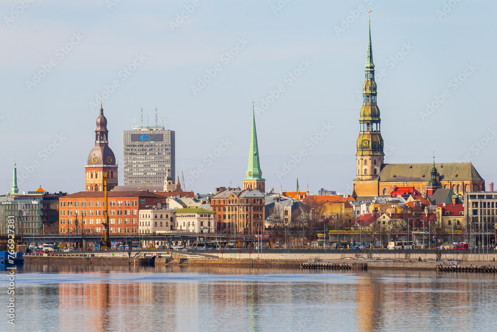 Fototapeta premium Riga towers and rooftops day time skyline. Sunny spring time shade on the buildings in Riga, next to a market and new project of railway in the Baltic States