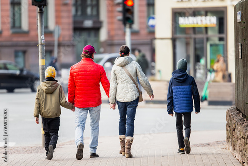 Family of four taking a walk on weekend in city holding hands and enjoying time together
