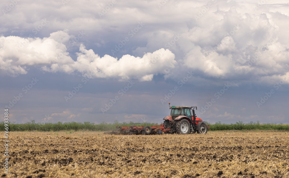 Obraz premium Tractor preparing land with seedbed cultivator.