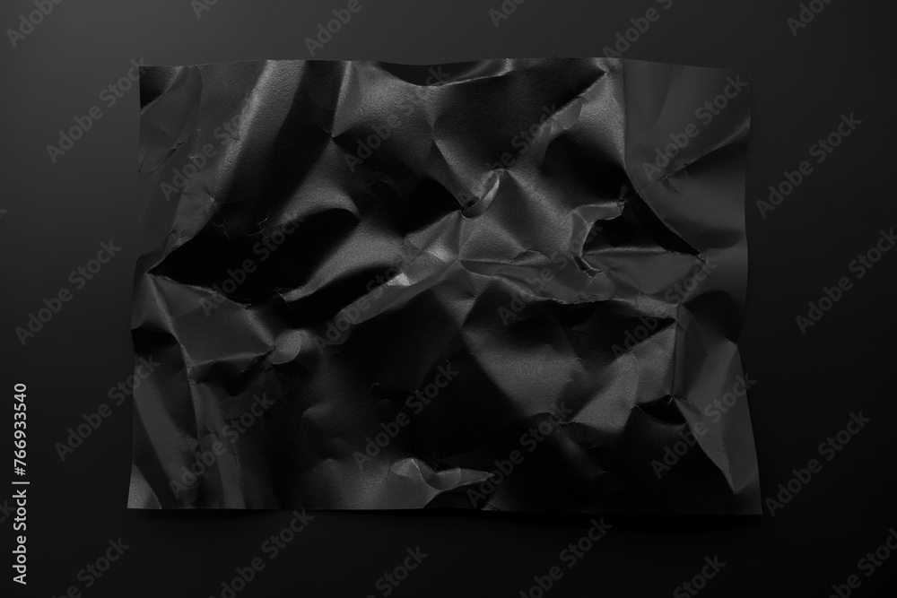 Black crumpled paper isolated on black background