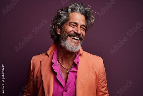 Portrait of a happy mature man with long grey hair and beard posing at studio. © Iigo