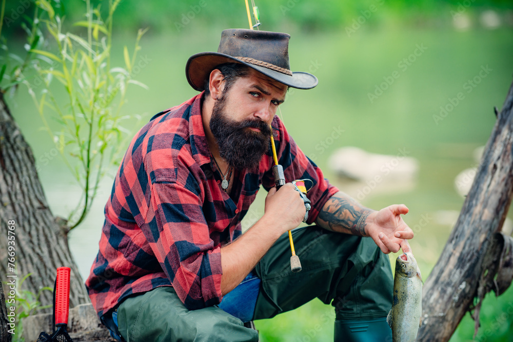 Young bearded man fishing at a lake or river. Flyfishing.