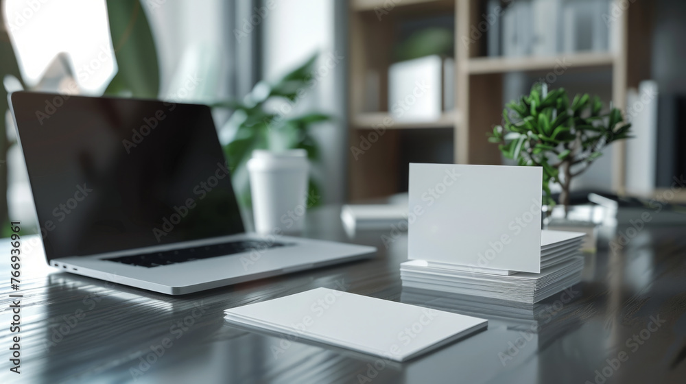 A modern workspace featuring a sleek laptop with a blank screen alongside stacks of blank business cards on a polished wooden desk. A modern workspace featuring a sleek laptop with a blank screen alongside stacks of blank business cards on a polished wooden desk.