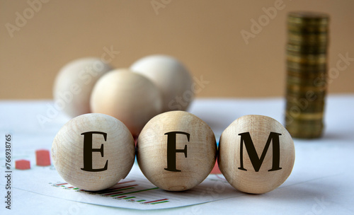 EFM - abbreviation on wooden balls on a background of coins and graphics. photo