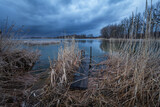 A pier in the reeds and a dark cloud over the lake