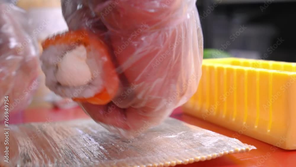 Close-up of chef slicing sushi using sushi mold on red board on table in restaurant, copy space