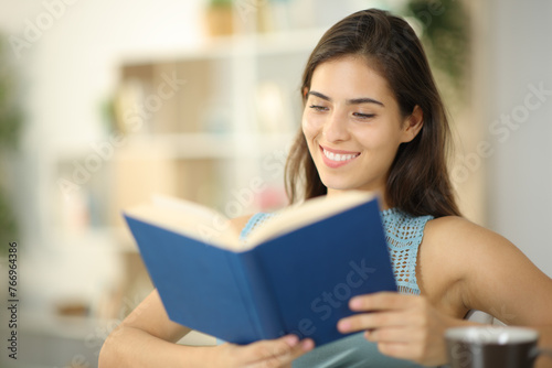 Happy woman is reading paper book at home
