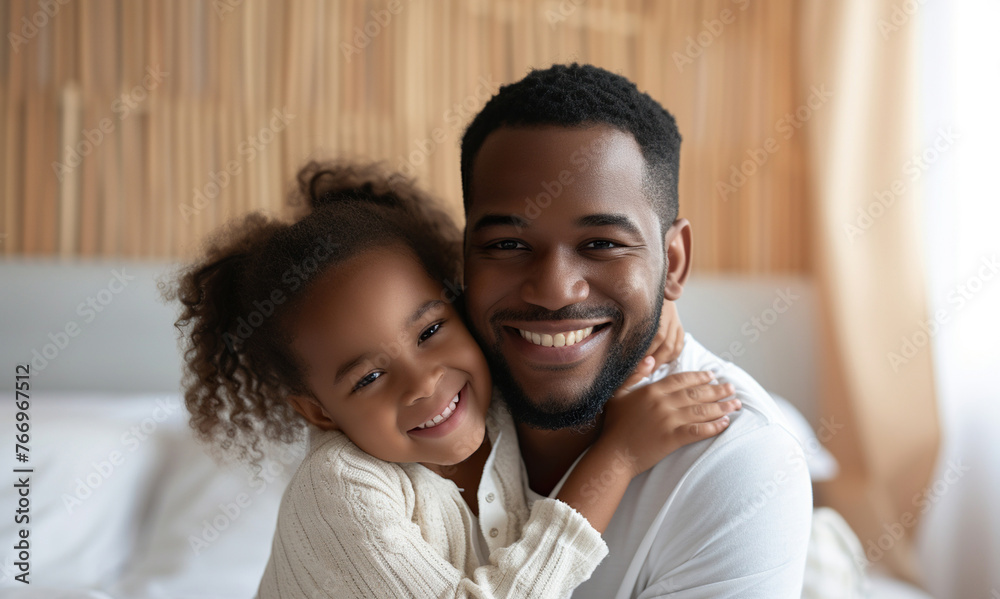 African American man and his little daughter hugging in bedroom African American man and his little daughter hugging in bedroom