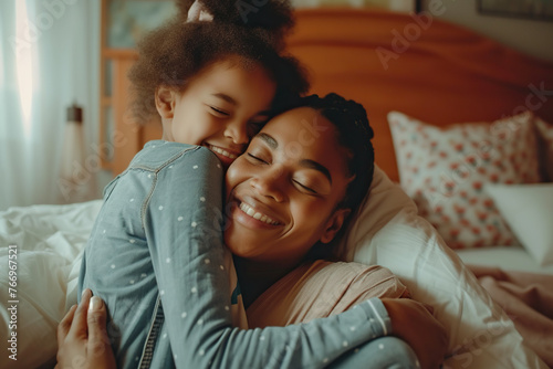 African American woman and her little daughter hugging in bedroom