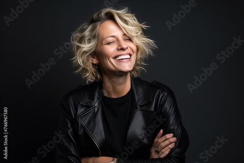 Portrait of a beautiful young woman laughing against a dark background.