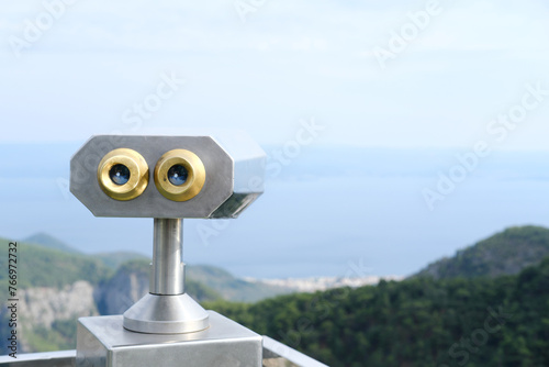 Touristic Telescope for Coastal Viewing on Clear Day. A fixed telescope stands ready for visitors to view the expansive coastline and clear blue skies.