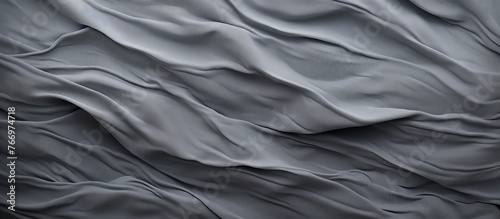 A close up of a grey satin bed sheet with waves pattern, resembling a landscape. The fabric is smooth and luxurious, creating an electric blue hue