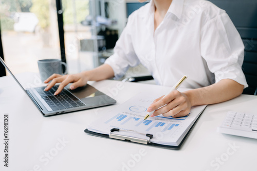 Confident businesswoman working on laptop tablet and smartphone at her workplace at office...